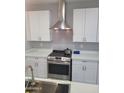 Close-up view of the kitchen's stainless steel stove, range hood, white cabinets, and elegant countertops at 4835 S 35Th Dr, Phoenix, AZ 85041