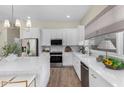 Modern white kitchen with stainless steel appliances, stone countertops, and a central island with breakfast bar at 523 W Bluejay Dr, Chandler, AZ 85286