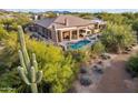 Back of house with a refreshing pool, covered patio, lounge chairs, and a natural desert landscape at 6128 E Brilliant Sky Dr, Scottsdale, AZ 85266