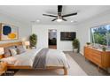 Cozy main bedroom with a ceiling fan, TV, large window, and view into the ensuite bathroom at 701 W Wilshire Dr, Phoenix, AZ 85007