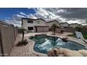 Backyard oasis features a lagoon-style pool, mature landscaping, and outdoor dining area at 14334 W Avalon Dr, Goodyear, AZ 85395