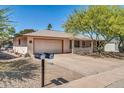 This property showcases a tidy front yard, long driveway, and attached two-car garage at 20006 N Concho Cir, Sun City, AZ 85373