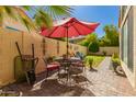 Cozy backyard patio with wrought iron furniture, a red umbrella, and paver flooring at 21 W Ranch Rd, Tempe, AZ 85284