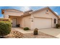 Beige home with desert landscaping and a two-car garage beneath a partly cloudy sky at 2429 E Valencia Dr, Casa Grande, AZ 85194