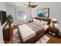 Comfortable main bedroom features a wooden bed frame, soft rug, ceiling fan, and a large window with natural light at 6633 W Orange Dr, Glendale, AZ 85301