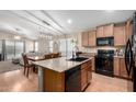 Open concept kitchen with wood cabinets, modern black appliances, and an island at 41655 W Somerset Dr, Maricopa, AZ 85138
