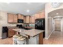 Kitchen island with seating, granite countertops, and stainless steel appliances at 41655 W Somerset Dr, Maricopa, AZ 85138