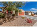 Single-story home featuring desert landscaping, a red garage door, and a tree providing shade to the house at 4402 W Bush Bean Way, San Tan Valley, AZ 85144