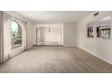 Open living room with neutral carpet, bright lighting, and a view into the dining area and kitchen at 10834 N 45Th St, Phoenix, AZ 85028
