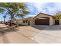 Charming single-story home with a well-maintained front yard, two-car garage and gated front door, all beneath a sunny, blue sky at 1133 E Juanita Ave, Gilbert, AZ 85234