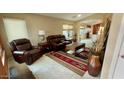 Inviting living room with leather furniture, area rug, and large windows at 1203 W Mesquite Tree Ln, San Tan Valley, AZ 85143