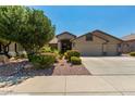 Inviting single-story home with well-maintained landscaping, desert rock and mature trees, and a convenient three-car garage at 13825 W Montebello Ave, Litchfield Park, AZ 85340
