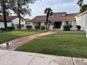Charming single-story home featuring a lush lawn, red-tiled roof, and a welcoming brick pathway to the entrance at 2701 E Lockwood St, Mesa, AZ 85213