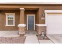 Close-up of the front door with stone accents on the porch columns at 37295 W Cannataro Ln, Maricopa, AZ 85138