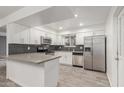 Updated kitchen features stainless steel appliances, gray quartz counters, subway tile backsplash, and wood-look tile flooring at 4207 W Mission Ln, Phoenix, AZ 85051