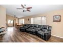 Spacious living room featuring modern flooring, a ceiling fan and a large leather couch at 5002 W Wikieup Ln, Glendale, AZ 85308