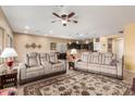 Bright, open-concept living room with plush seating, a ceiling fan, and seamless flow to the dining area at 5548 W Victory Way, Florence, AZ 85132