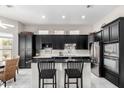 Modern kitchen features black cabinets, stainless steel appliances, and a breakfast bar at 5670 W Irma Ln, Glendale, AZ 85308