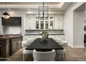 Stylish dining area with designer lighting, custom cabinetry, and backyard views through steel-framed glass doors at 6500 E Cactus Wren Rd, Paradise Valley, AZ 85253