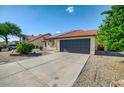 View of the home's front exterior featuring a two-car garage and desert landscaping at 7102 W Julie Dr, Glendale, AZ 85308