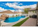 A rock waterfall feature adds a touch of nature to the backyard pool and patio area at 714 W Desert Hills Dr, San Tan Valley, AZ 85143