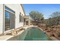 Tranquil backyard pool featuring a rock waterfall and mature landscaping at 14287 W Cora Ln, Goodyear, AZ 85395