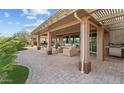 Covered back patio with pavers, comfortable seating, and a built-in grill for outdoor dining at 27248 W Mohawk Ln, Buckeye, AZ 85396