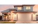 Two-story home featuring a tile roof, arched entryway, well-manicured lawn, and a two-car garage at 7953 W Topeka Dr, Glendale, AZ 85308