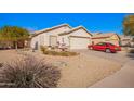 Charming single-story home featuring a well-manicured yard, desert landscaping and a classic red car in the driveway at 10664 E Emerald Ave, Mesa, AZ 85208