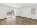 Bright, empty living room featuring wood floors, neutral paint, a large sliding glass door, and lots of natural light at 15397 W Hackamore Dr, Surprise, AZ 85387