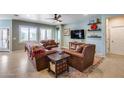 Inviting living room featuring comfortable leather seating, a ceiling fan, and bright windows at 20194 N Riverbank Rd, Maricopa, AZ 85138