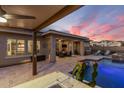 Inviting backyard with a pool, spa, covered patio, outdoor seating, and a view of a colorful sunset at 30331 N 115Th Ln, Peoria, AZ 85383