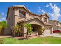 Tan two-story home with desert landscaping including small palm trees on a green lawn at 3907 N 143Rd Ln, Goodyear, AZ 85395