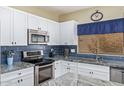 Modern kitchen featuring white cabinets, stainless steel appliances, granite counters, and blue backsplash at 3907 N 143Rd Ln, Goodyear, AZ 85395