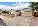 View of the house with its neutral color, brick accents, and wide two-car garage at 6335 E Brown Rd # 1081, Mesa, AZ 85205