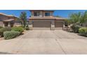 Two-story tan home with a three car garage and desert landscaping at 6350 W Hess St, Phoenix, AZ 85043