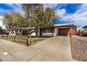 Inviting single-story home featuring a spacious driveway, mature trees, and tasteful landscaping at 6720 W Medlock Dr, Glendale, AZ 85303