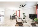 Open-concept living and dining area features tile flooring, modern ceiling fan, and neutral decor with pops of color at 10825 W El Cortez Pl, Peoria, AZ 85383