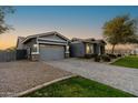 A single-story home with gray stucco, a stone-accented garage, a paver driveway, and desert landscaping at 12962 N 145Th Ave, Surprise, AZ 85379