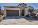 A tan single-story home showcasing a two-car garage and an arched gate entrance at 1775 E Tangelo Pl, Queen Creek, AZ 85140
