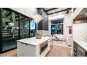 Modern kitchen featuring a white island, pendant lighting, and floor-to-ceiling sliding glass doors to outdoor living space at 4434 E Camelback Rd # 128, Phoenix, AZ 85018