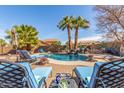Relaxing backyard oasis with a sparkling pool, waterfall feature, palm trees, and comfortable lounge seating at 4937 W Desert Hollow Dr, Phoenix, AZ 85083