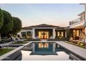 Luxury backyard featuring a pool reflecting the house, lush greenery, and elegant outdoor furniture at 5915 E Calle Del Sud --, Phoenix, AZ 85018