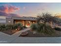 Stunning home exterior featuring desert landscaping, a covered porch, and a cozy bench at sunset at 669 W Chaparral Rd, Wickenburg, AZ 85390