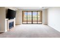 Bright living room with balcony access, fireplace, and neutral carpeting at 7175 E Camelback Rd # 307, Scottsdale, AZ 85251