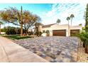 Beautiful home showcasing a well manicured front lawn, desert trees and an inviting paver driveway leading to a two car garage at 8713 N 80Th Pl, Scottsdale, AZ 85258