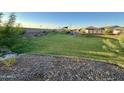 Landscaped common area featuring a grassy lawn, stone accents, and community playground at 9737 W Agora Ln, Tolleson, AZ 85353