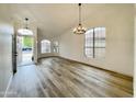 Open living room with vaulted ceilings, wood-look tile floors, a modern chandelier, and a large windows at 9761 W Yukon W Dr, Peoria, AZ 85382