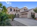 Elegant two-story home featuring a three-car garage, arched entryway, gated courtyard, desert landscaping and a tile roof at 15635 W Montecito Ave, Goodyear, AZ 85395