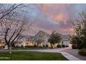 Dramatic shot of a light-colored brick home at sunset with lovely landscaping and walkway at 20406 E Sunset Ct, Queen Creek, AZ 85142